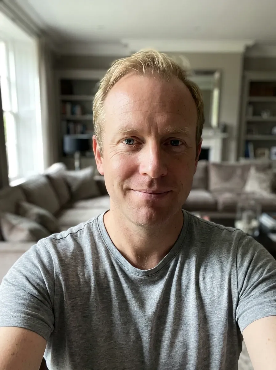 Original selfie input — blond man in a gray T-shirt indoors